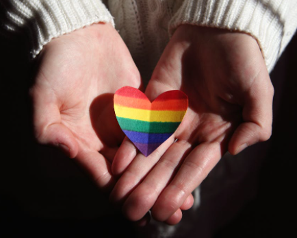 Hands holding a rainbow heart