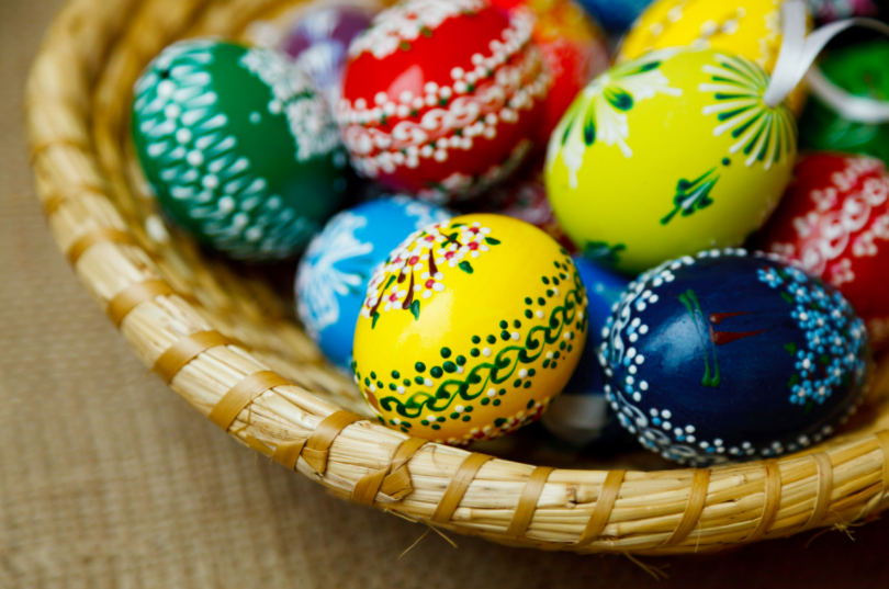 A basket of brightly painted eggs of various colors. 