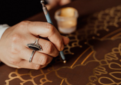 Hand painting gold designs on a table.